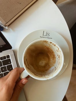 A hand holds an empty coffee cup at Lis Espresso & Patisserie, İzmir.