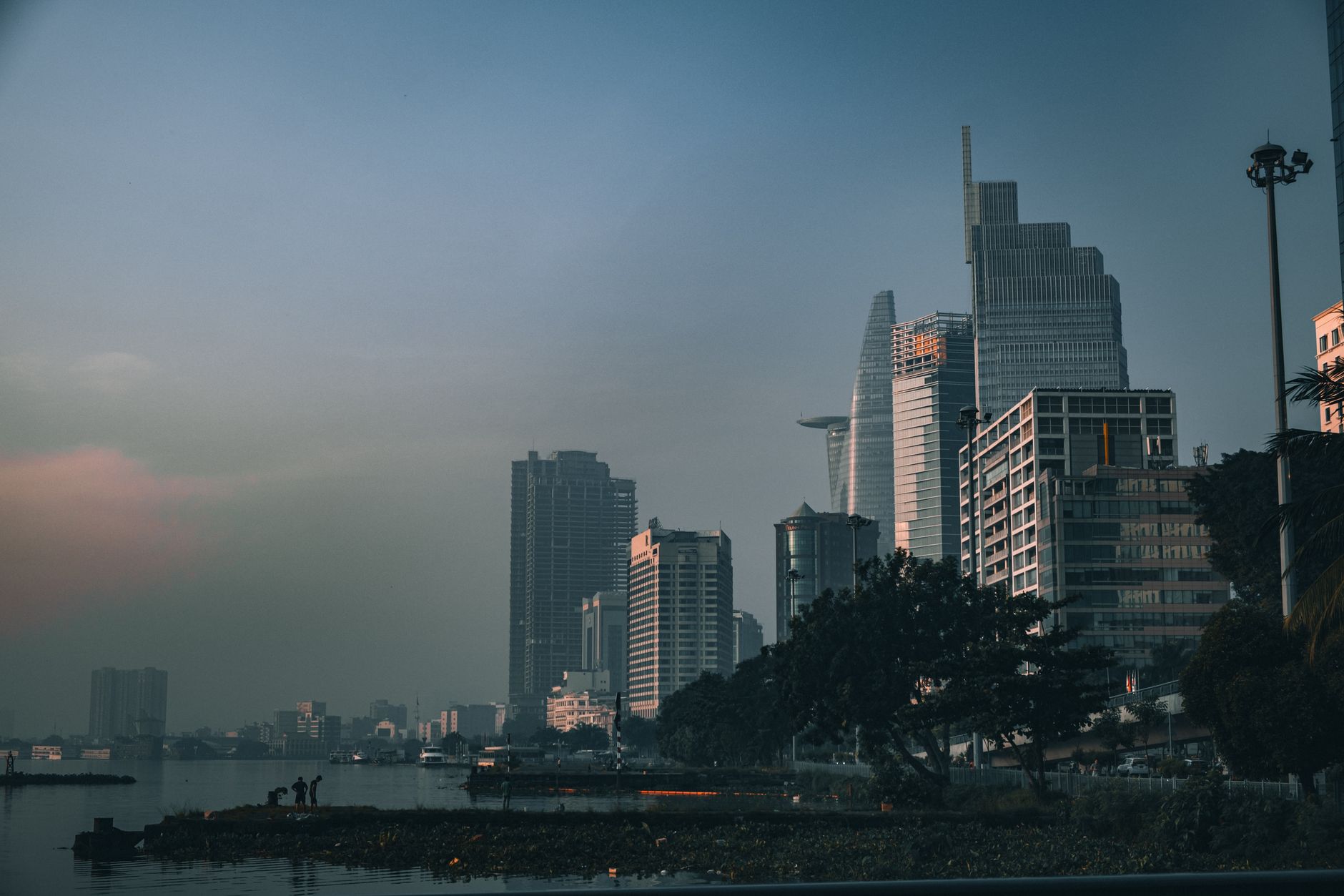 Dramatic view of Ho Chi Minh City's skyline reflecting on the calm river at twilight.