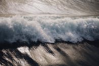 一个惊人的捕捉海浪撞上海滩与阳光斑驳的海泡沫