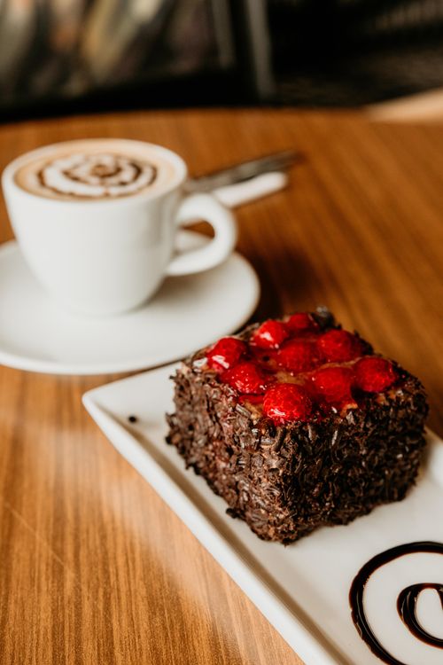Free Indulge in a rich chocolate cake topped with berries, paired with a cappuccino. Stock Photo