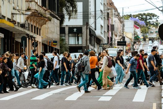 A lively crosswalk filled with people in downtown Curitiba, Brazil showcasing urban life.