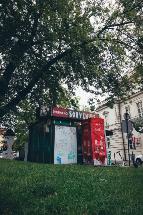 Free A quaint souvenir kiosk stands nestled among trees in a bustling urban park. Stock Photo