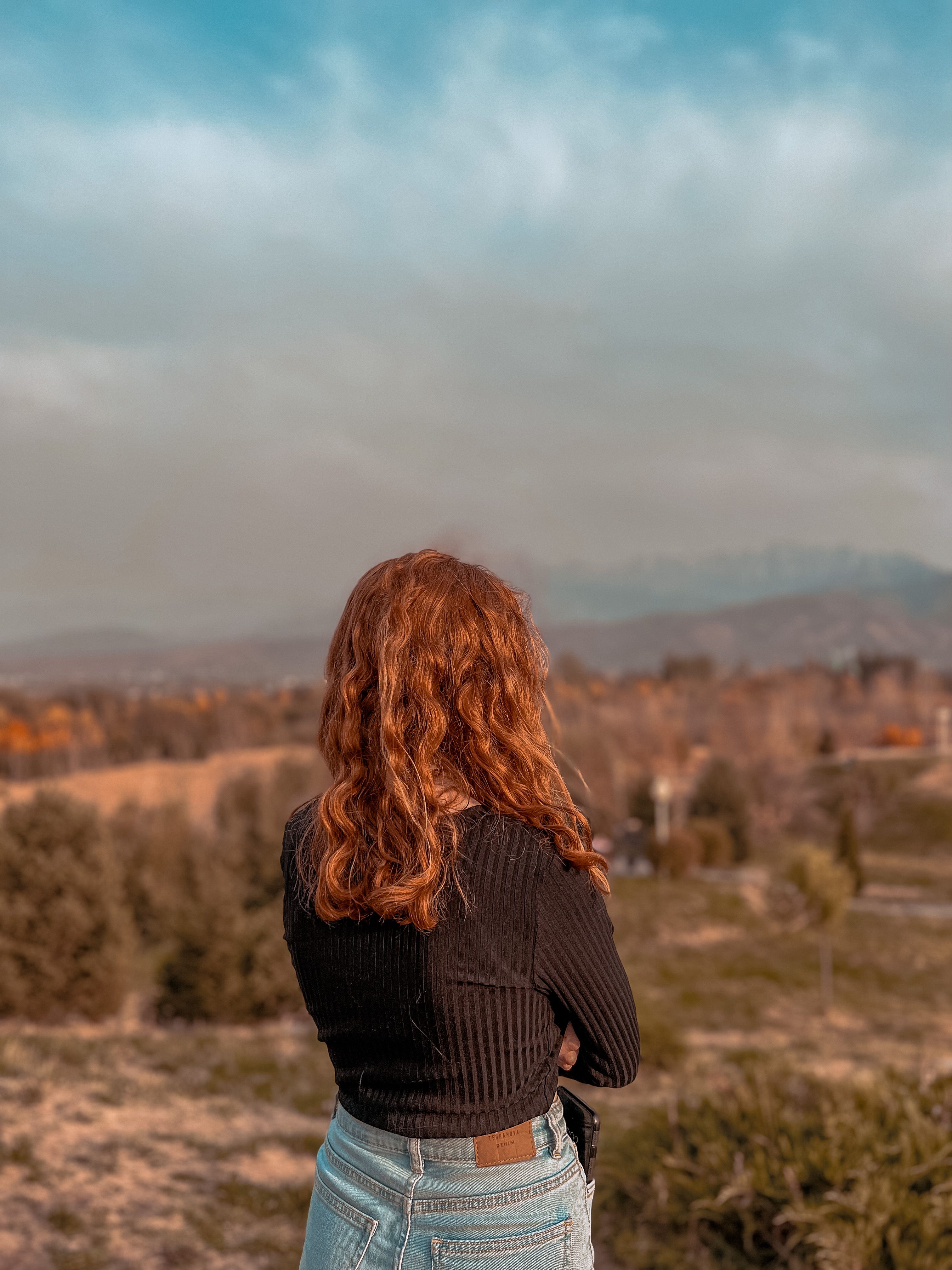 Woman with Wavy Red Hair Looking Into the Distance · Free Stock Photo