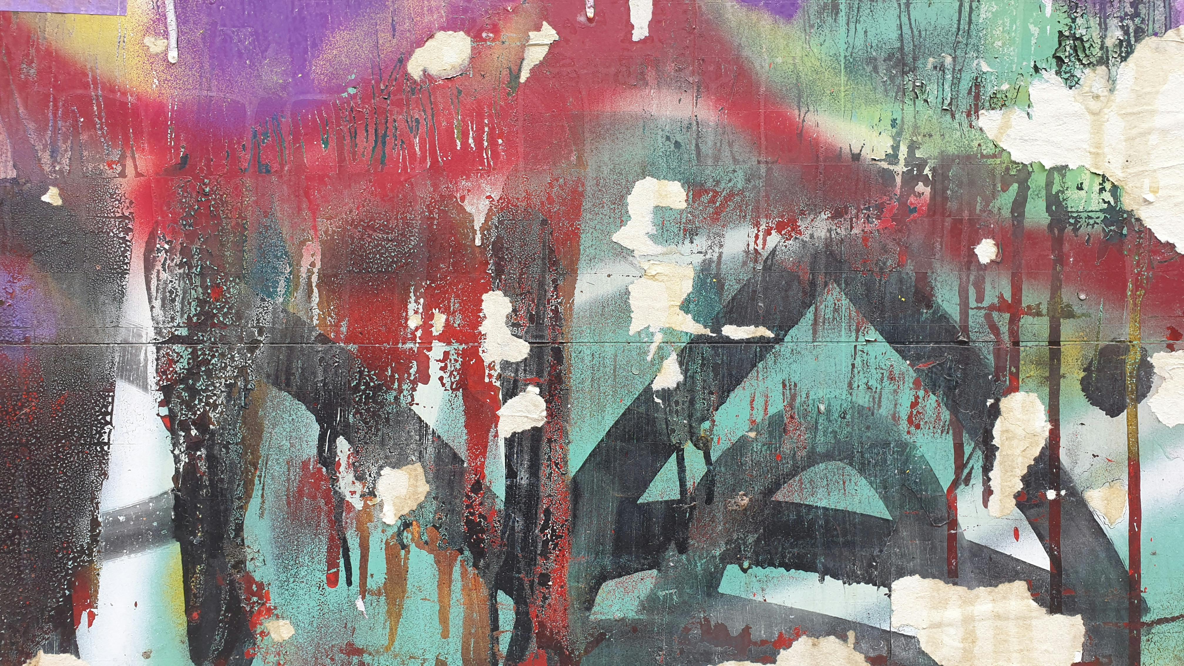Colorful abstract graffiti art on a worn urban wall, showcasing bold textures and layers.