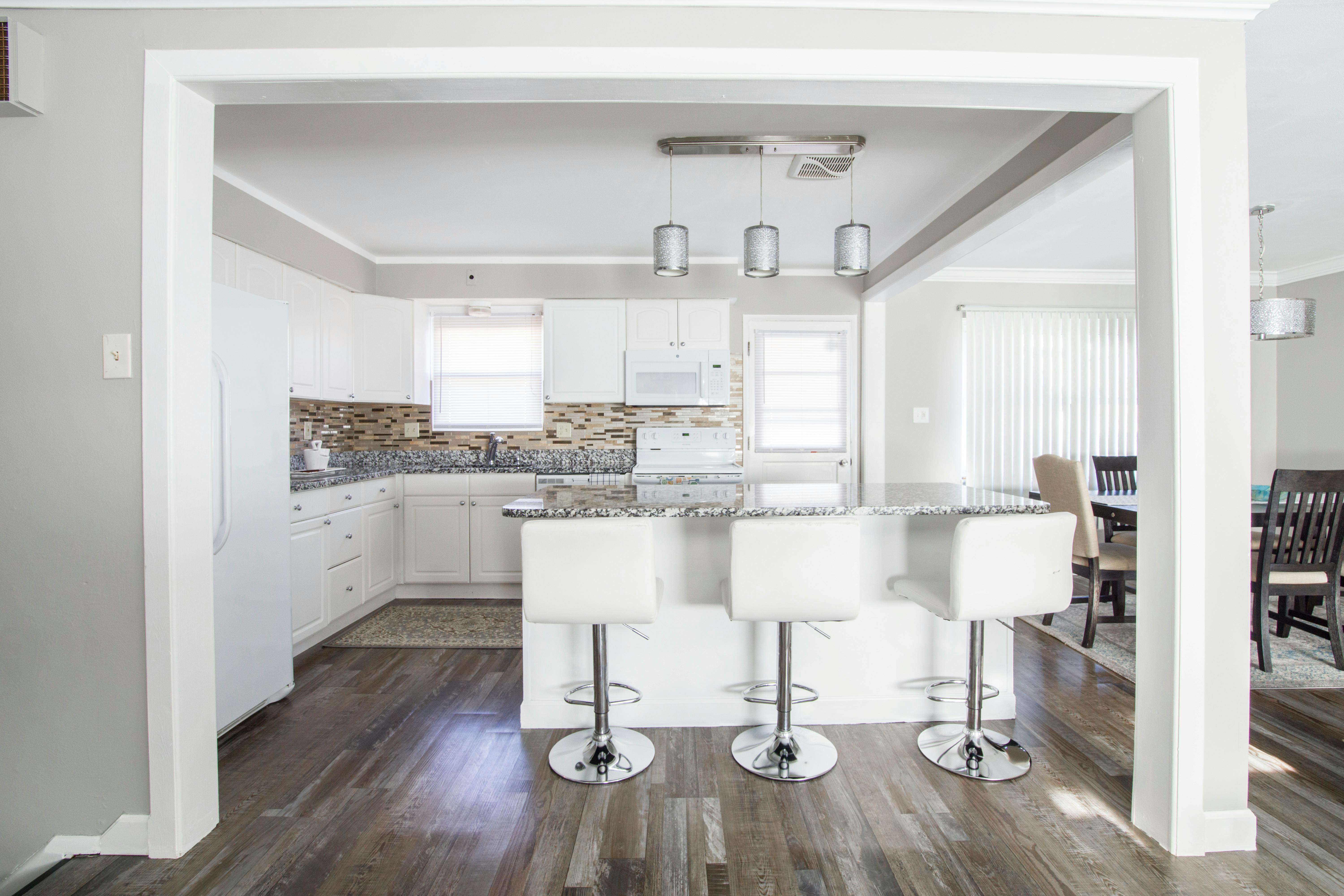 Three White Barstools in Front of Kitchen Island
