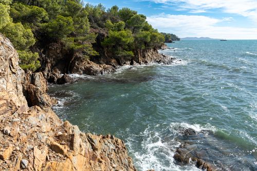 Free A scenic view of rugged cliffs meeting the ocean under a clear blue sky, surrounded by lush greenery. Stock Photo