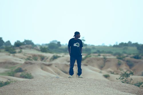 Young Man in a Casual Outfit Standing on a Sandy Hill