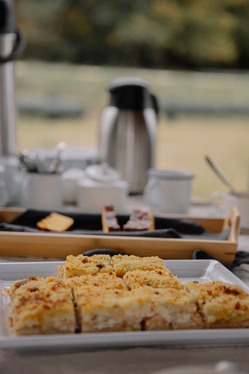 Free Close-up of crumbly dessert squares on a plate with a picnic setup outdoors, featuring a blurred background. Stock Photo