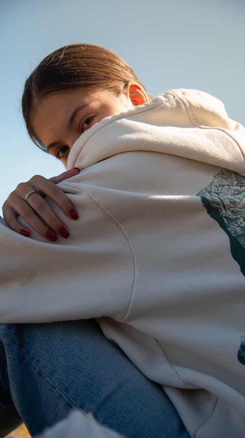 Sitting Woman Hiding Face behind Hood