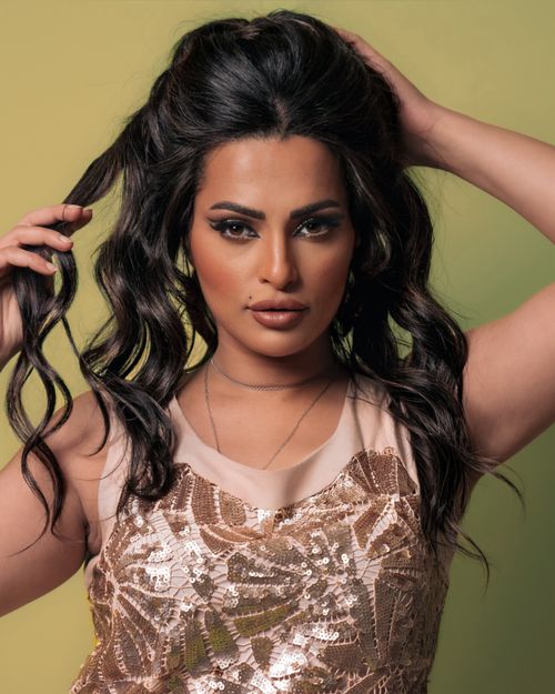 Free Stunning portrait of a young woman in a gold sequin dress against a green background. Stock Photo