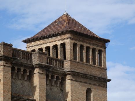 Close-up view of a medieval tower with brick architecture against a blue sky.