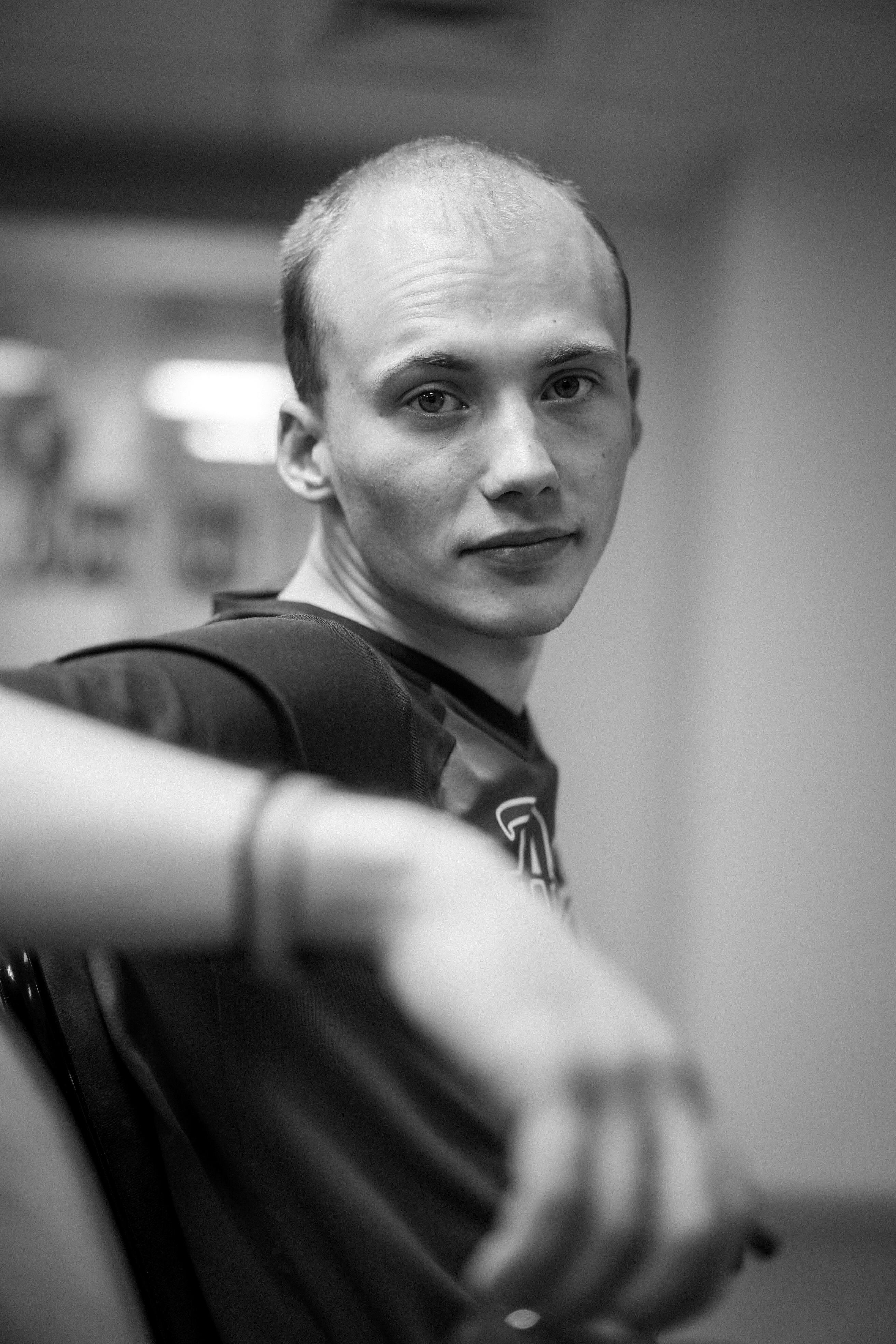 Black and white portrait of a balding man sitting and posing in a contemplative manner indoors.