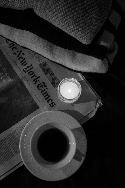 Free Moody black and white photo of coffee, candle, and newspaper on a cozy table. Stock Photo