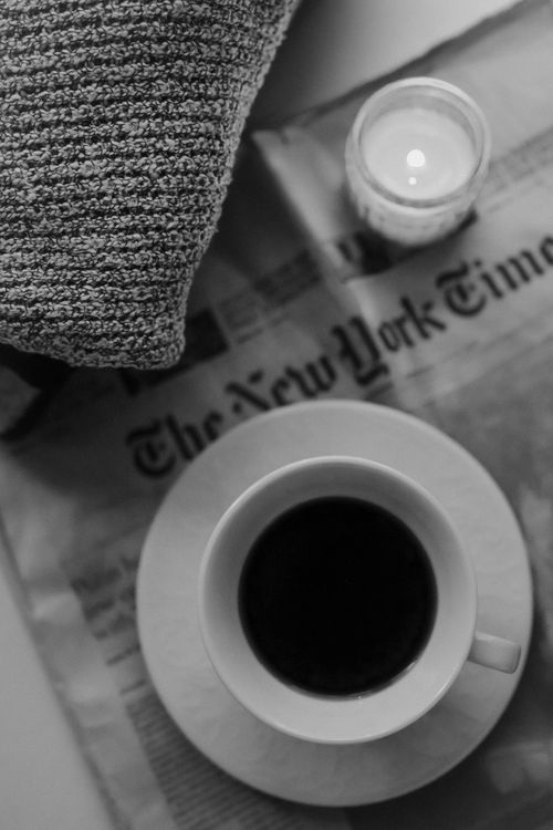 Free A black coffee cup and candle on a newspaper, perfect for a cozy morning. Stock Photo