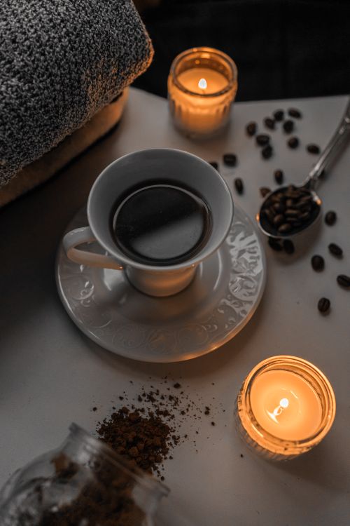 Free Warm candlelight ambiance with coffee cup, beans, and cozy atmosphere. Stock Photo
