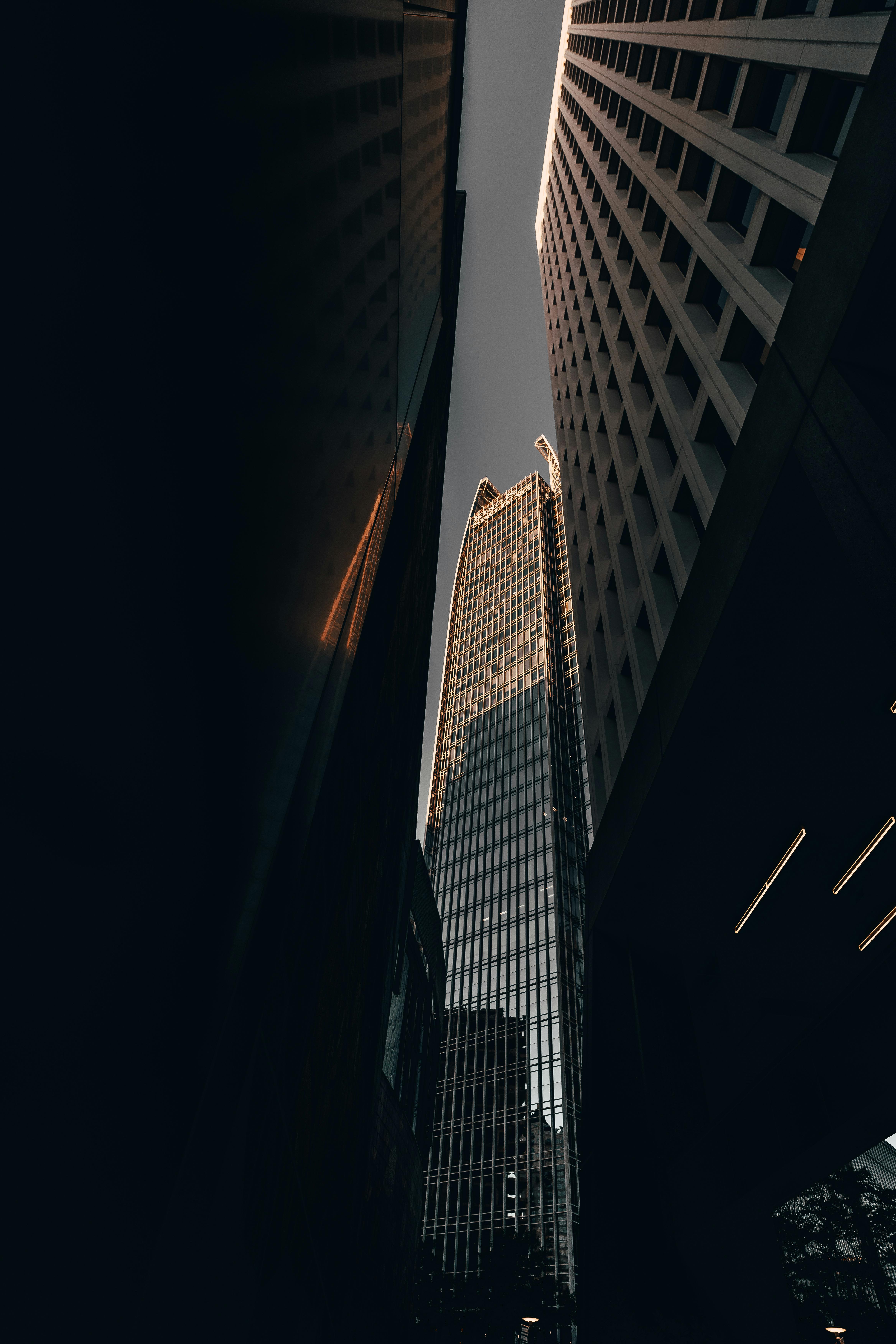 A towering skyscraper in a modern cityscape illuminated by striking light and shadows.