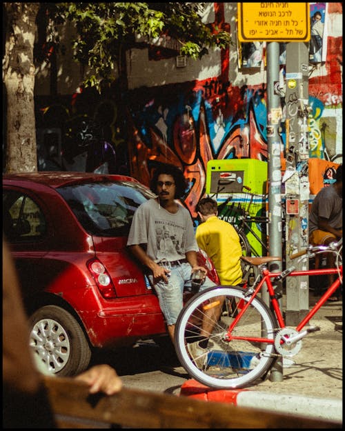 Man Leaning on a Car with a Glass in Hand