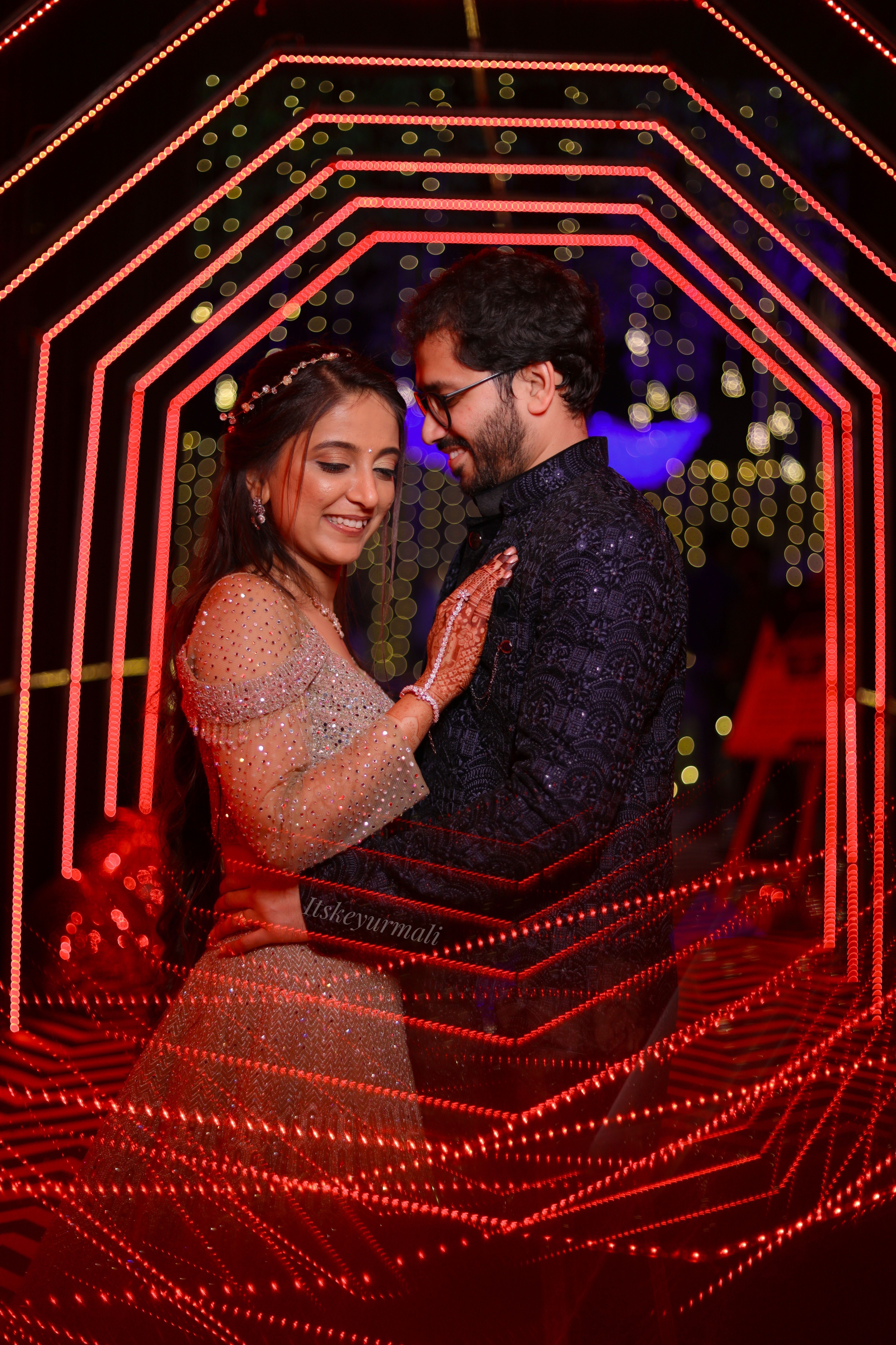 Elegant married couple embracing amidst dreamy evening lights.