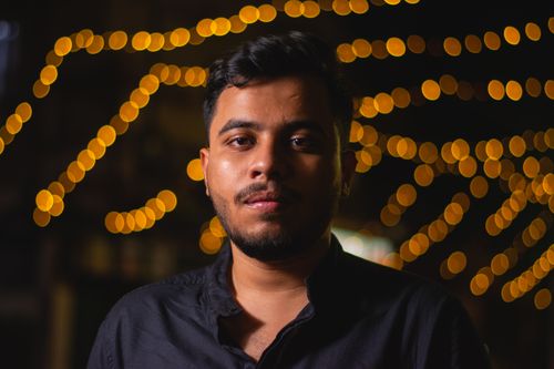 Free A close-up portrait of a young man at night with warm bokeh lights in the background. Stock Photo