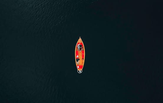 Aerial shot of a boat with people in Giethoorn, Netherlands, on calm waters.