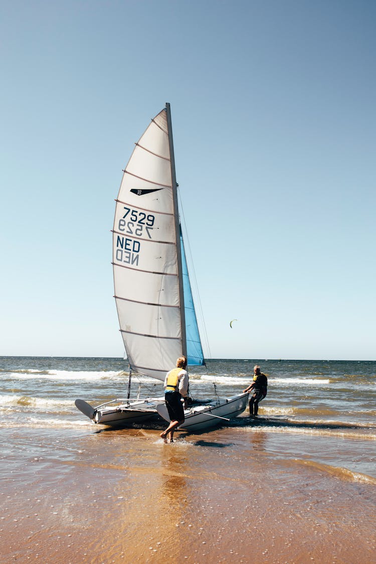 Two Windsurfers On The Beach