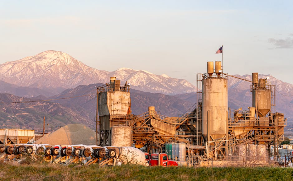 Cement factory in Redlands, CA with mountains and American flag at sunset.