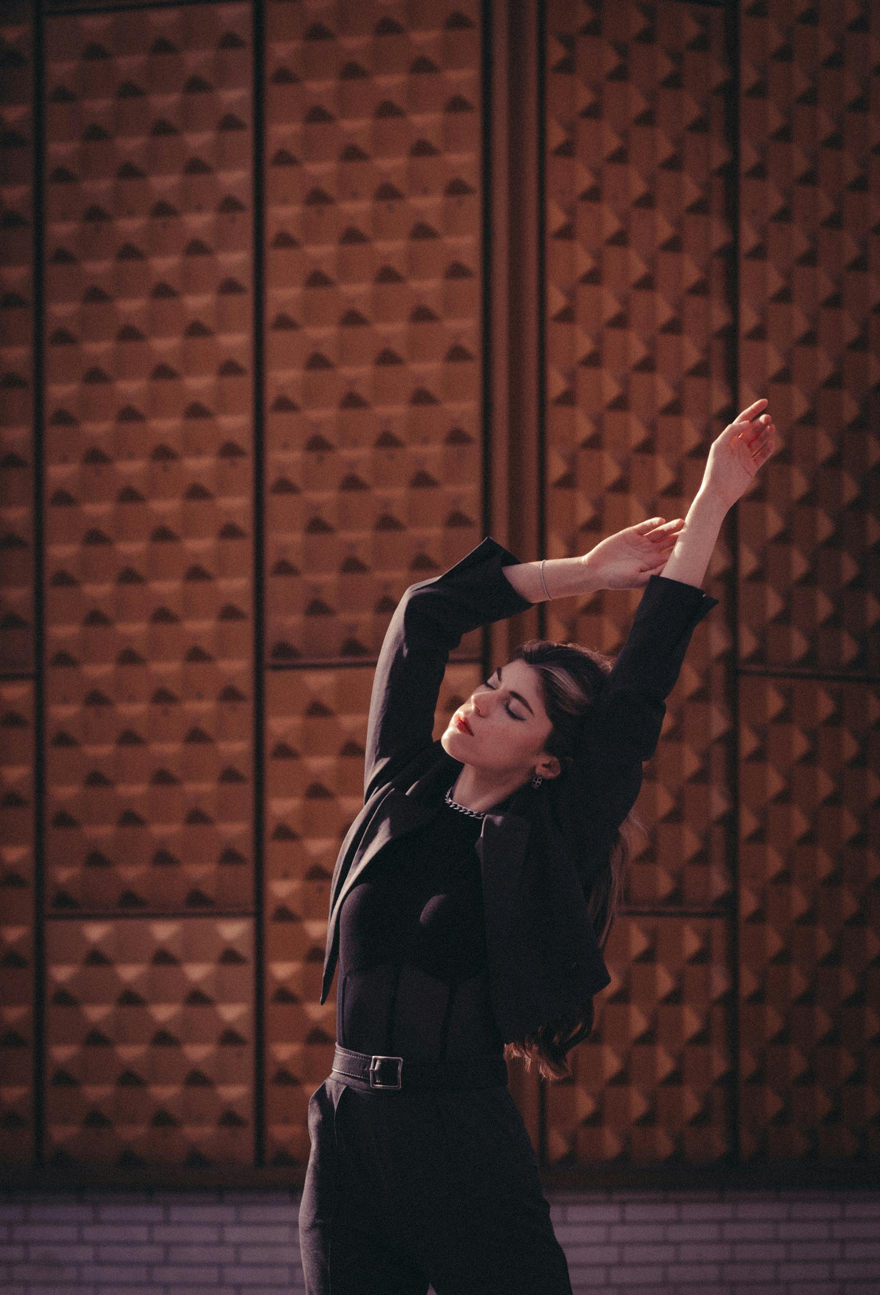 Elegant female dancer in Berlin, posing against a geometric background, eyes closed in concentration.
