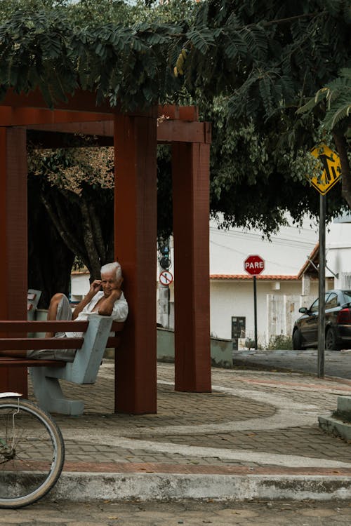 Elderly Man Sitting on a Bench in a City Square 