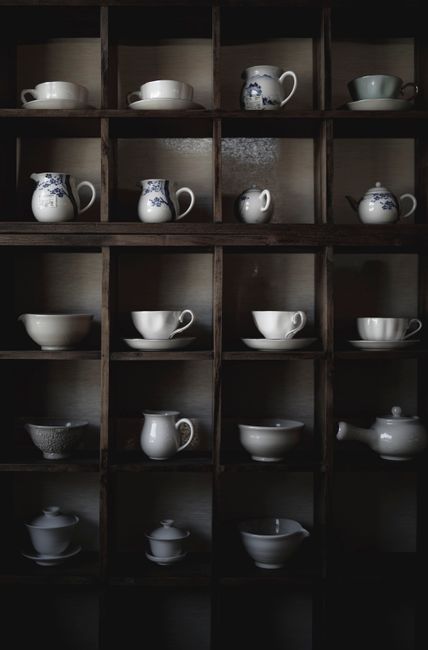 A sophisticated display of ceramic cups and teapots on wooden shelves, showcasing elegant design.
