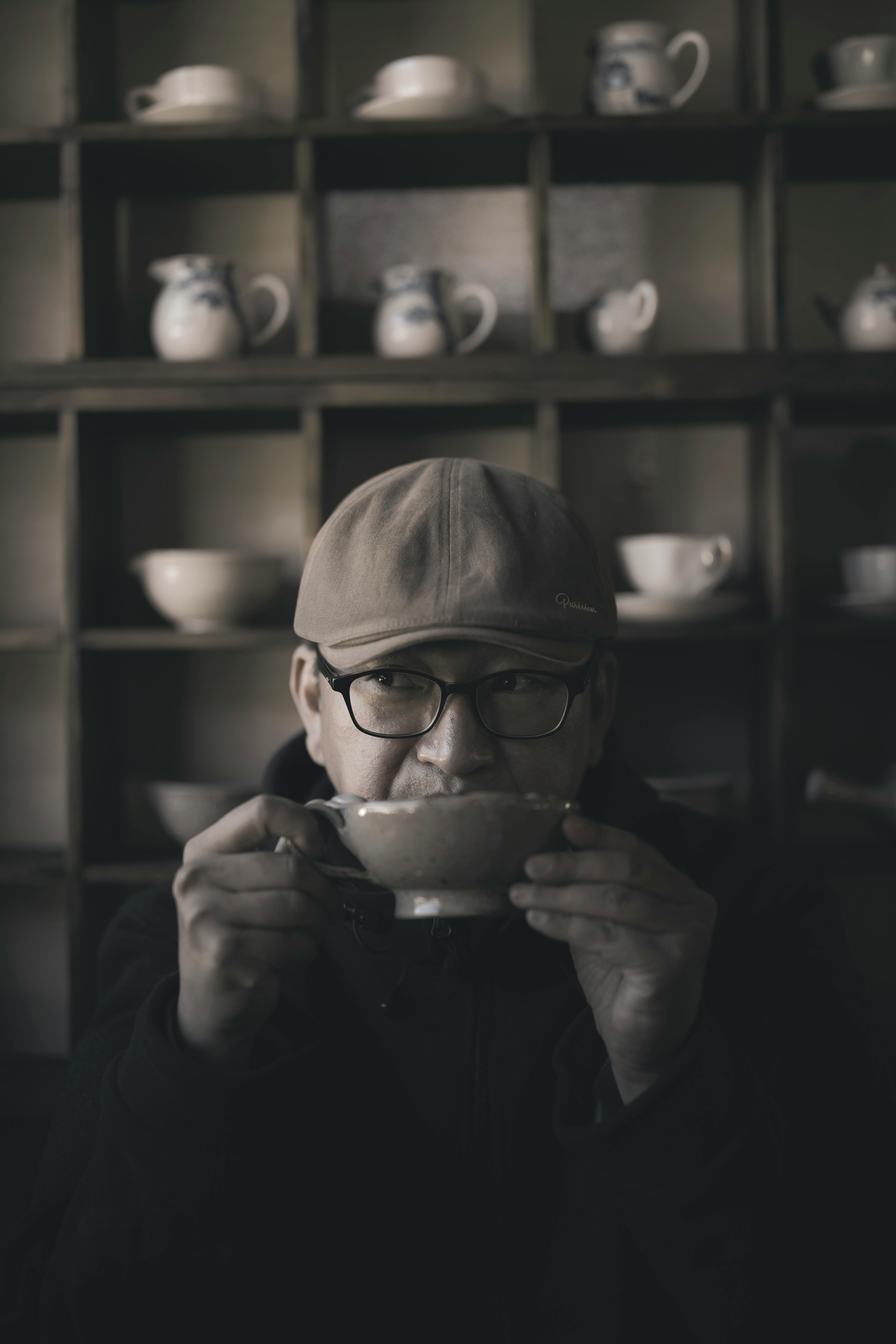 man in cap and eyeglasses holding cup