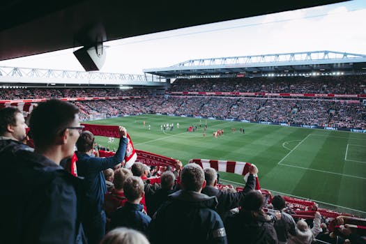 Fans cheer as players take the field at a vibrant football stadium, creating an electric atmosphere. by Tembela Bohle