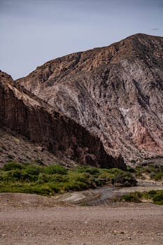 A dramatic mountain landscape with steep rock formations and sparse greenery.