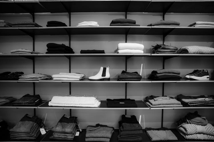 Grayscale Photography Of Assorted Apparels On Shelf Rack