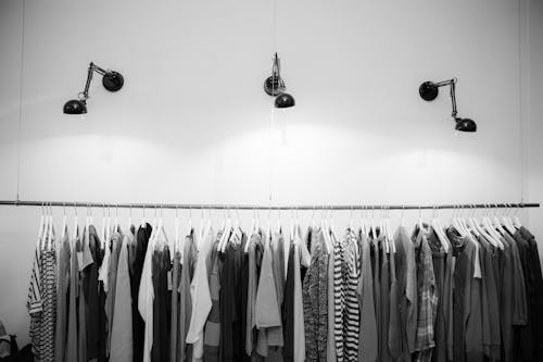 Фотография в градациях серого разных рубашек, висящих на вешалке для одежды