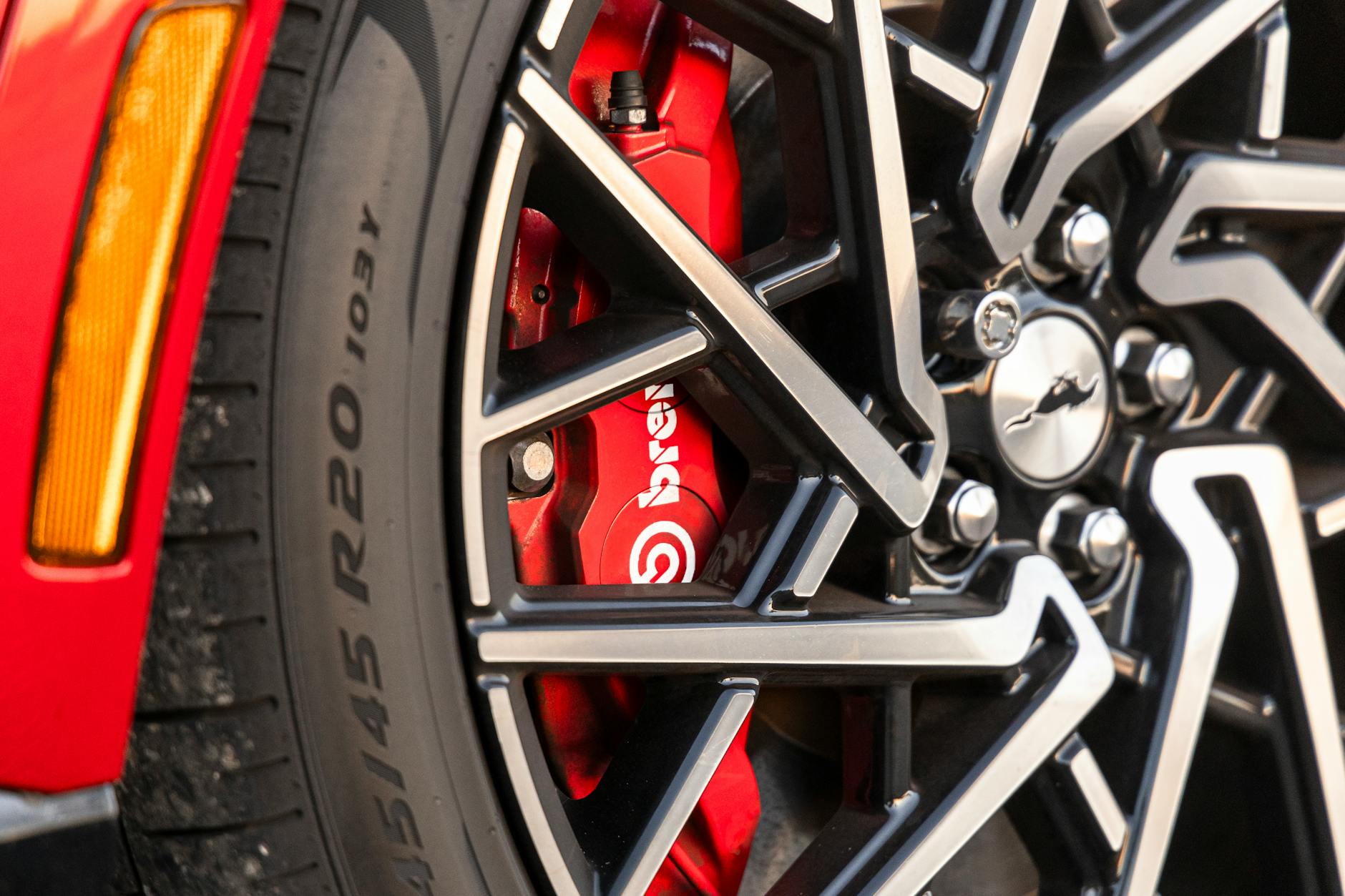 The front wheel of a red sports car with red brake calipers