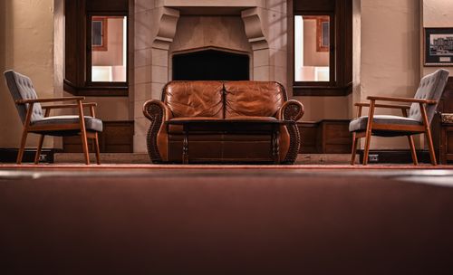Free A vintage style living room featuring a leather couch, armchairs, and a classic fireplace. Stock Photo