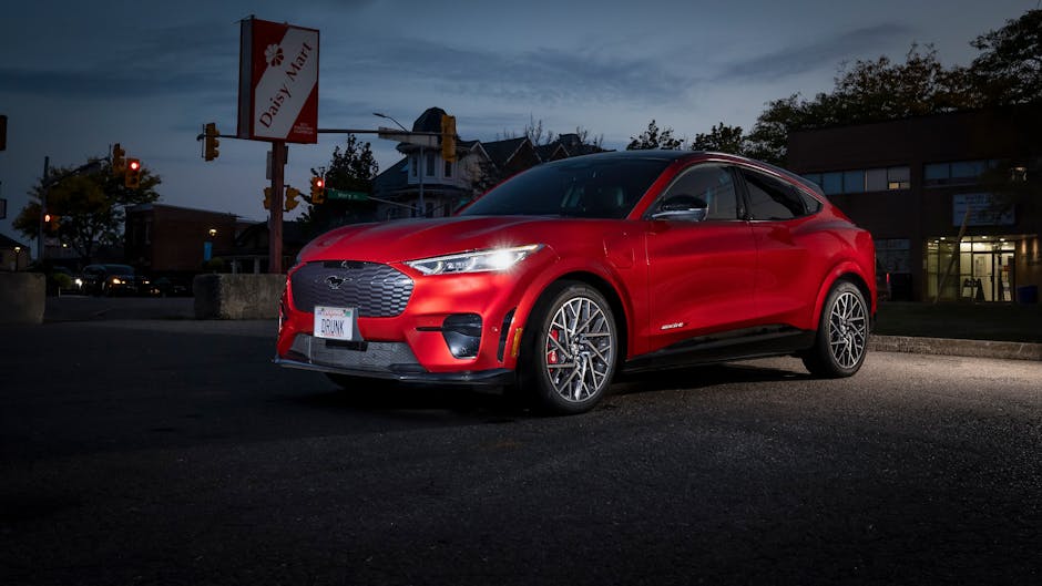 Red Ford Mustang Mach-E electric SUV parked at night in an urban setting.
