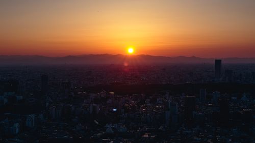 Free Breathtaking sunrise over Tokyo cityscape with vibrant orange and yellow hues illuminating the skyline. Stock Photo