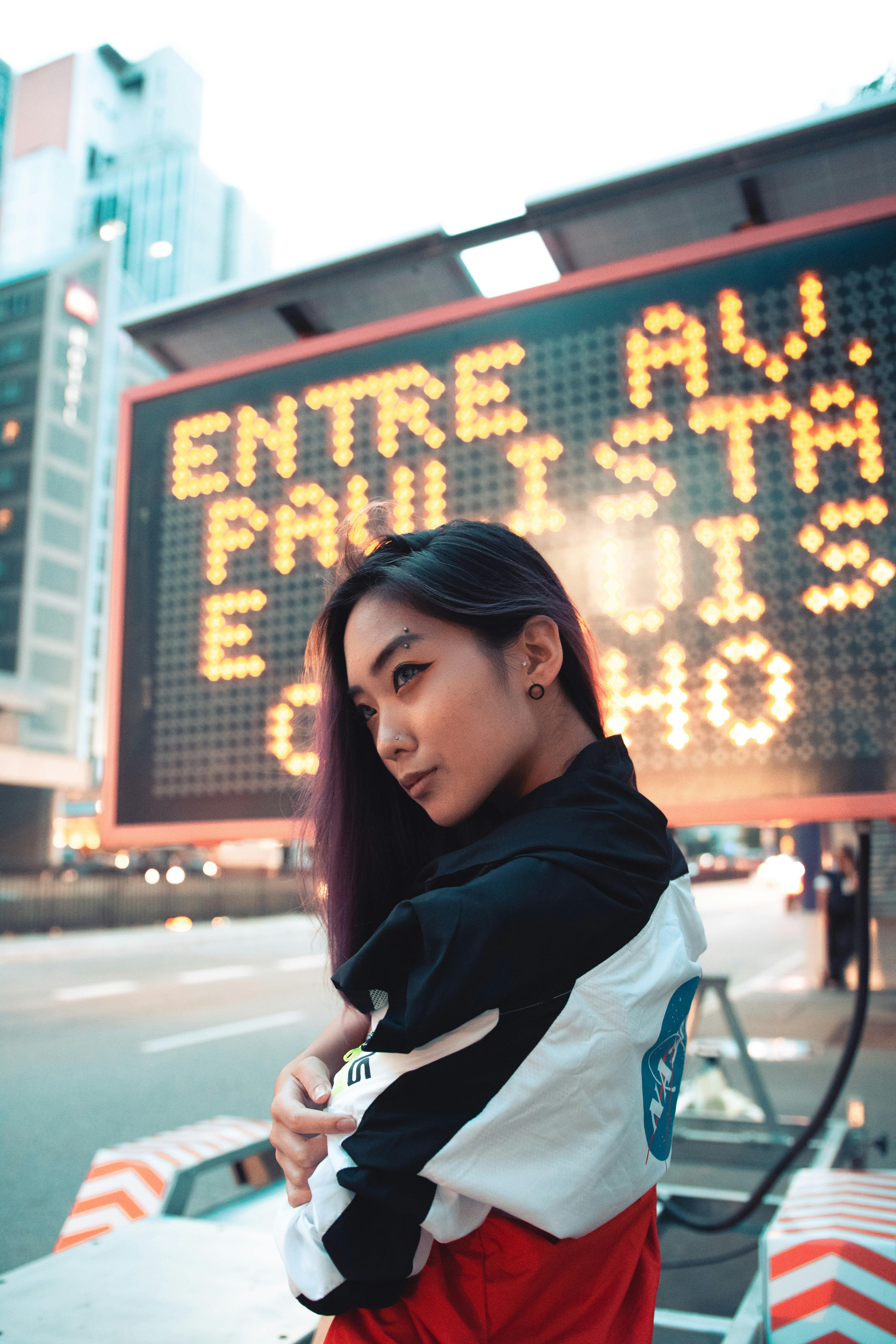 selective focus photography of woman wearing jacket near led signage