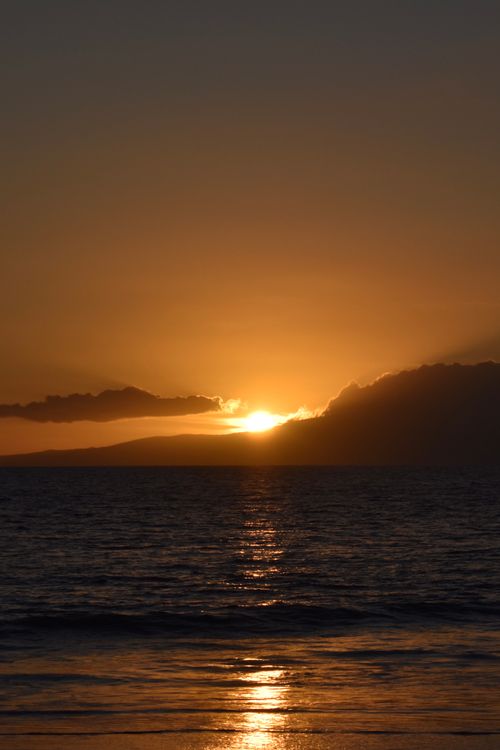 Free A tranquil sunrise over the ocean with a glowing horizon and gentle waves. Stock Photo