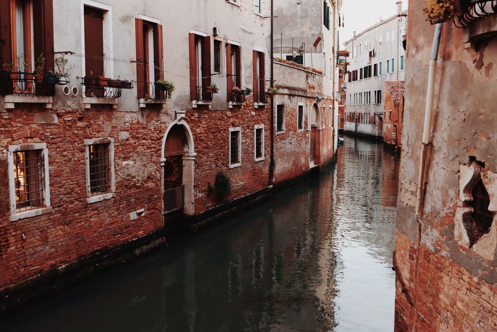 Canal venețian mărginit de clădiri mediteraneene rustice