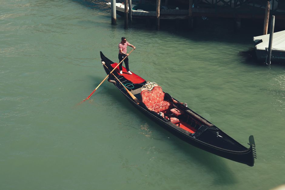 A traditional gondolier paddles through a canal in beautiful Venice, Italy.
