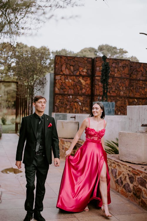 Woman in a Pink Dress and a Man Wearing a Black Suit, Going Together for a Party