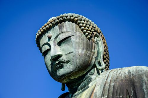 Free Detailed view of the Great Buddha statue in Kamakura under a clear blue sky. Stock Photo