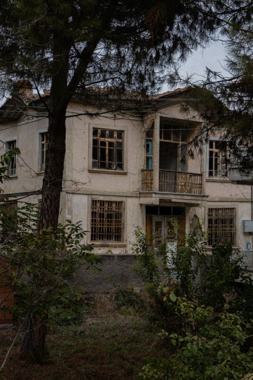 Free An abandoned house with broken windows and overgrown garden, creating a haunting vibe. Stock Photo