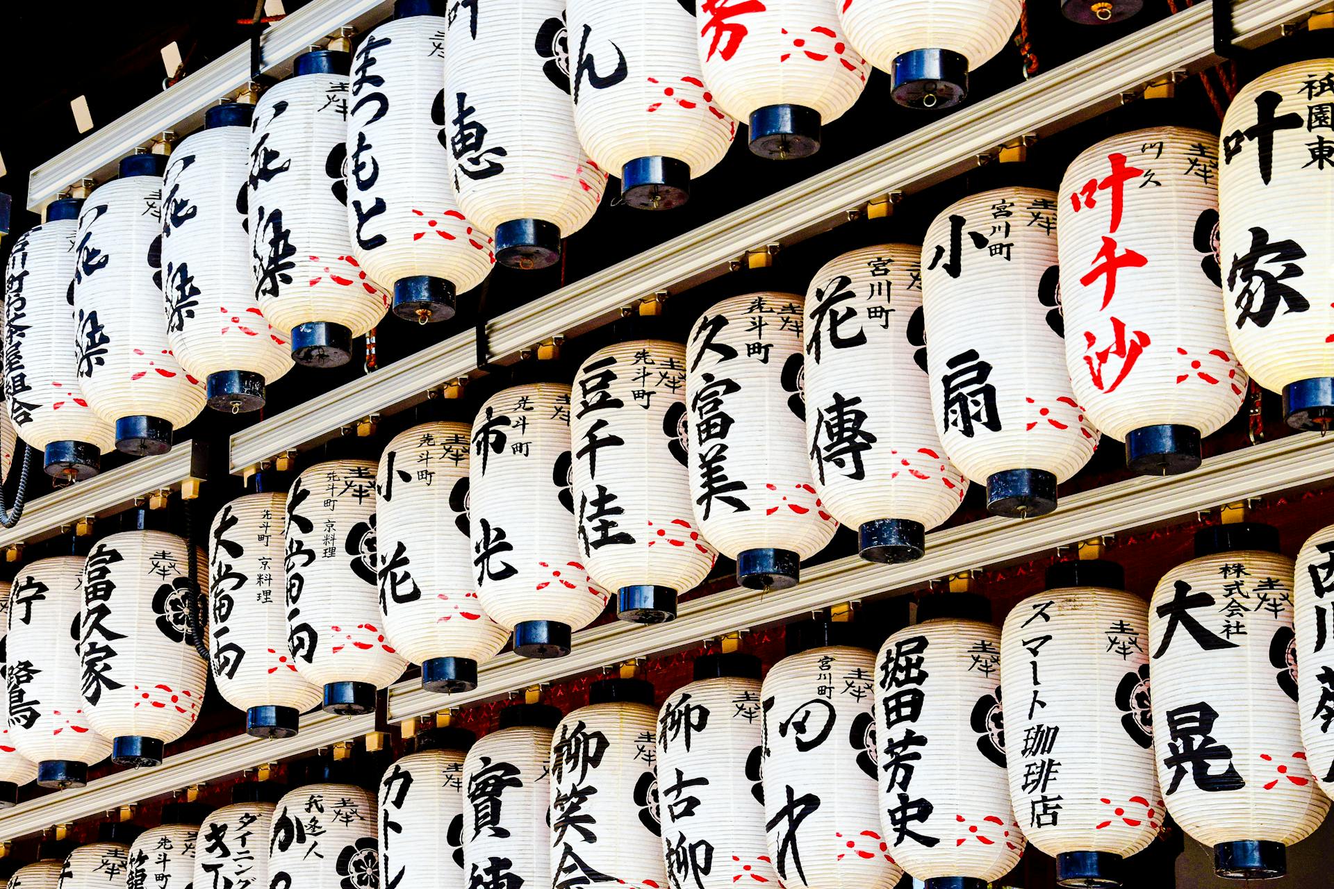 Japanese paper lanterns with calligraphy in Kyoto temple setting.