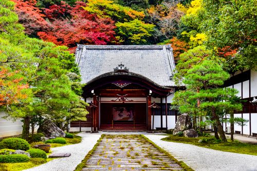 Free A traditional Japanese temple surrounded by vibrant autumn foliage in a serene garden setting. Stock Photo