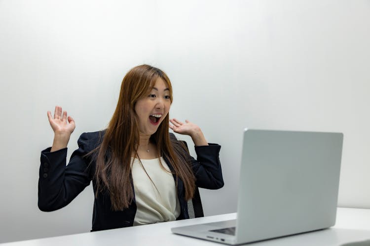 Woman Celebrating In Front Of A Laptop In An Office 