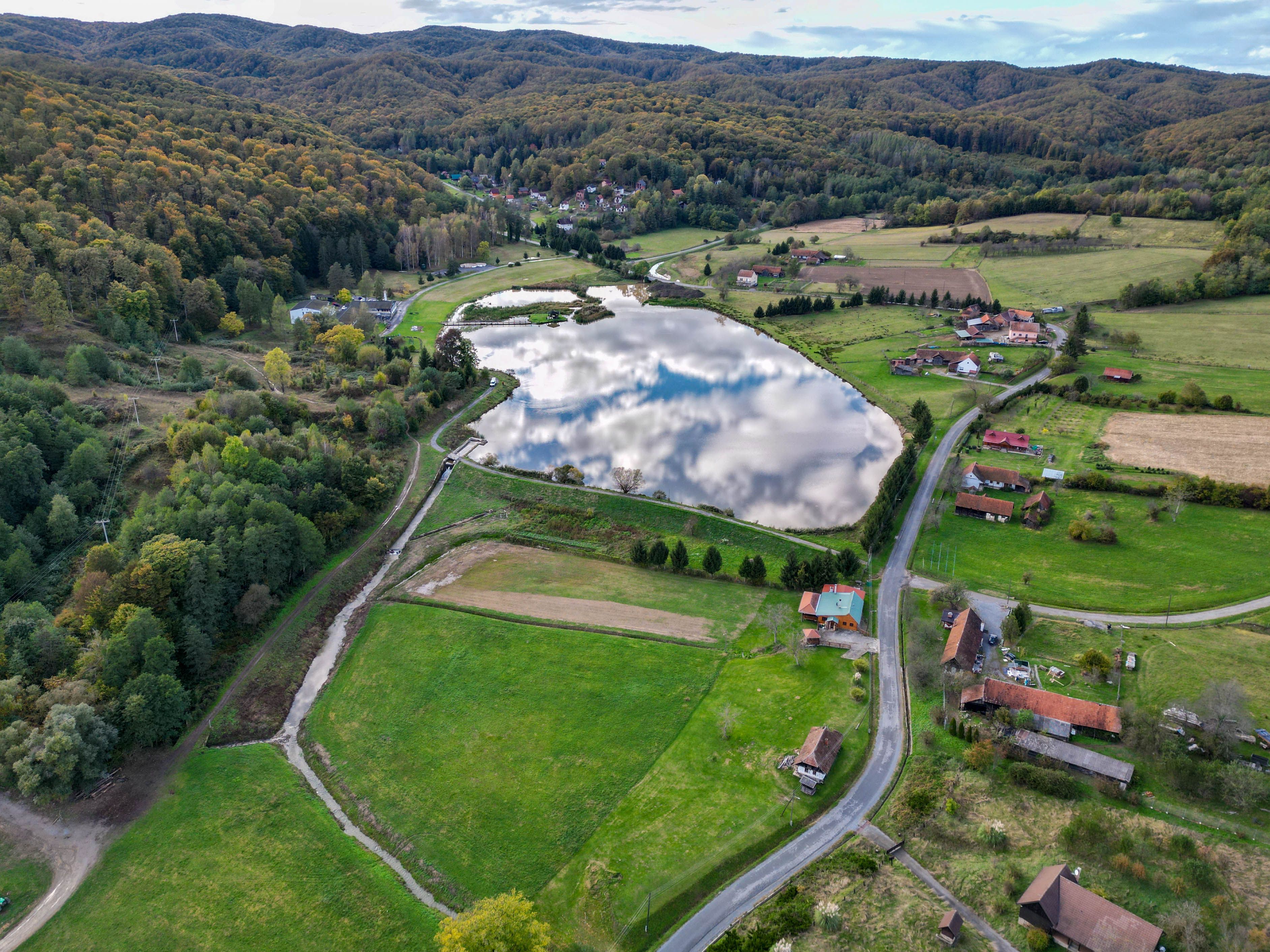 Aerial view of the scenic rural landscape in Podgarić, Croatia with fields, a lake, and rolling hills.