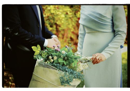 Close-up of a couple holding a floral basket, highlighting elegant wedding attire.
